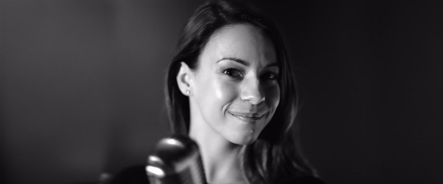 Portrait noir et blanc d'Adeline Chetail, comédienne voix off Sonacom, souriante devant un micro vintage