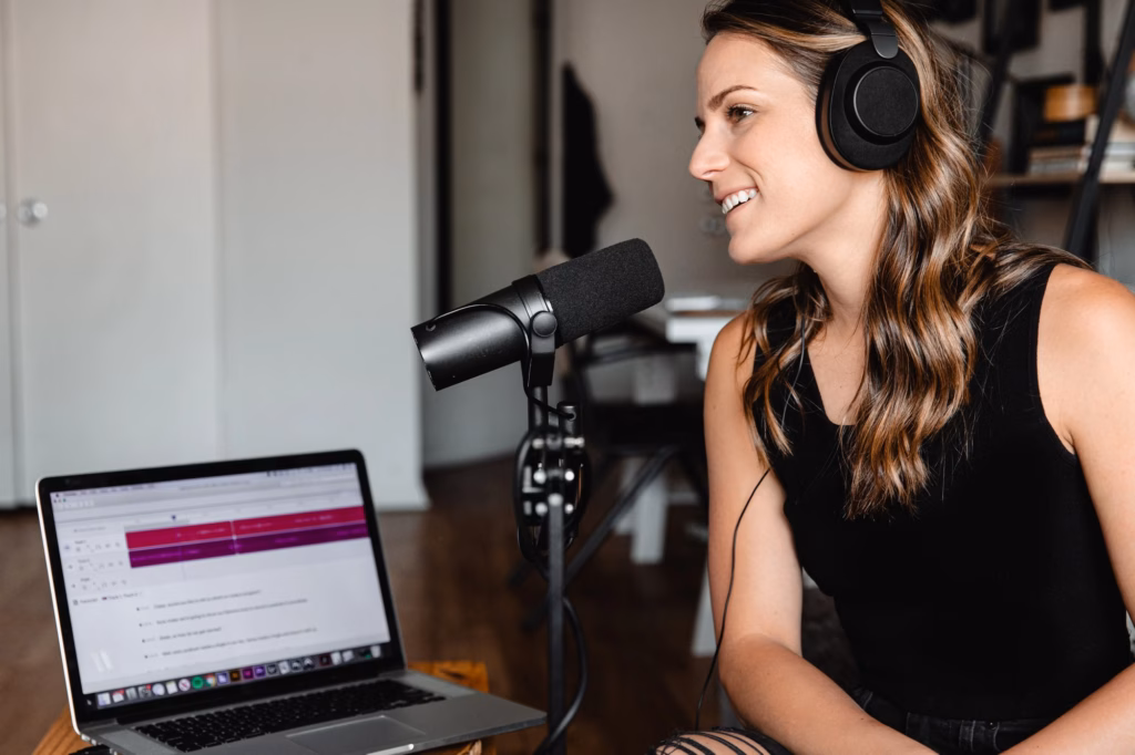 Femme au casque enregistrant un podcast devant son micro et son ordinateur