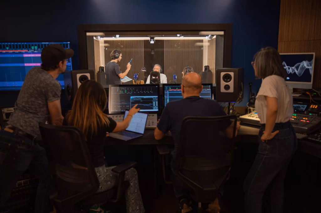 Équipe en régie et cabine vitrée pendant une session d'enregistrement