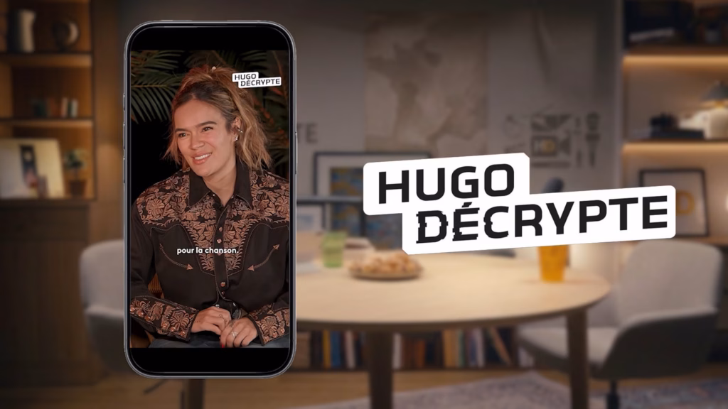 Karol G en interview sur un smartphone à côté du logo HugoDécrypte, captation réalisée par Sonacom